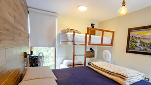 A room with a bunk bed, a desk with a chair, a fan, and a painting on the wall. - HOP Bali Exclusiva Laguna y Playa en Chincha (El Carmen)