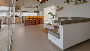 A spacious living area with a high ceiling, wooden beams, and a kitchen in the background. - HOP Macao Hermosa Casa de Playa (El Carmen)