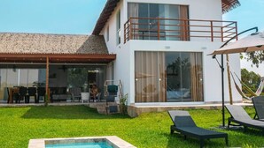 A modern two-story house with a large glass balcony, a swimming pool, and outdoor furniture. - HOP Macao Hermosa Casa de Playa (El Carmen)