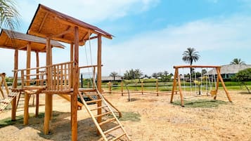 A wooden play structure with a climbing ladder and a covered seating area.