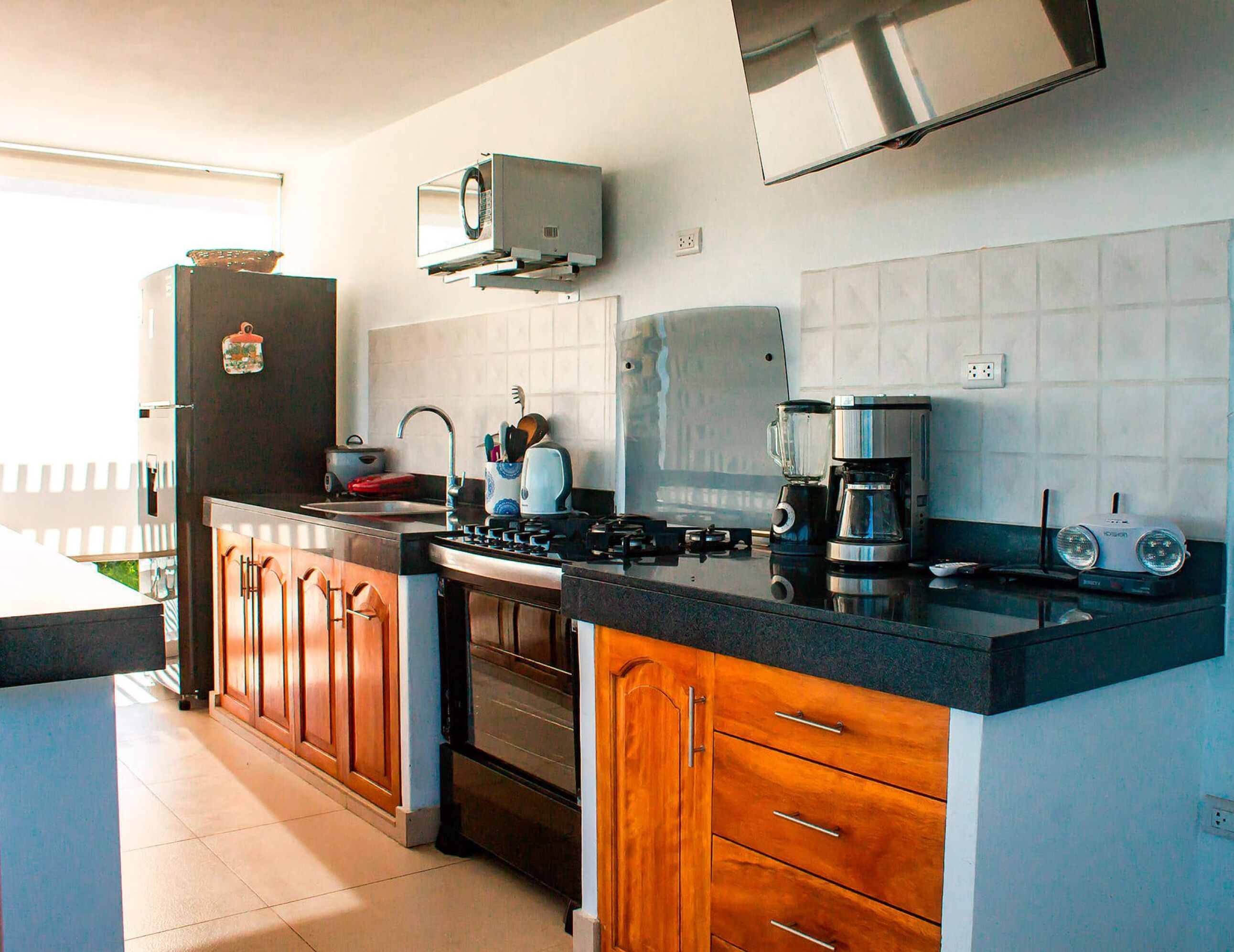 Une cuisine moderne avec des meubles en bois, une cuisinière encastrée et une machine à café.