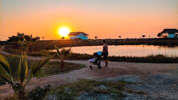 A sunset view with a house and a body of water.