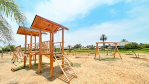 A wooden play structure with a ladder and swings in a sandy area with palm trees and a clear sky. - HOP Solarena Hermosa Casa Playa y Campo (Tambo de Mora)