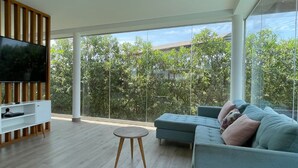 A modern living room with a large TV, a sofa, and a wooden TV stand. - HOP Odaiba Exclusiva Laguna y Playa en Chincha (El Carmen)