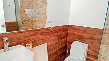 A modern bathroom with a white sink, a toilet, and a glass shower enclosure.