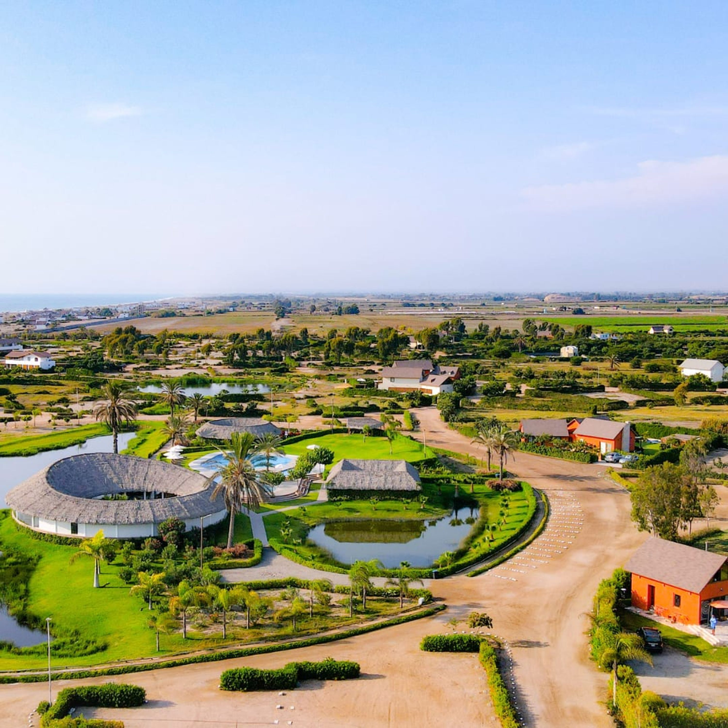 Een resort met ronde gebouwen, een centraal waterpartij en een verzorgd landschap.