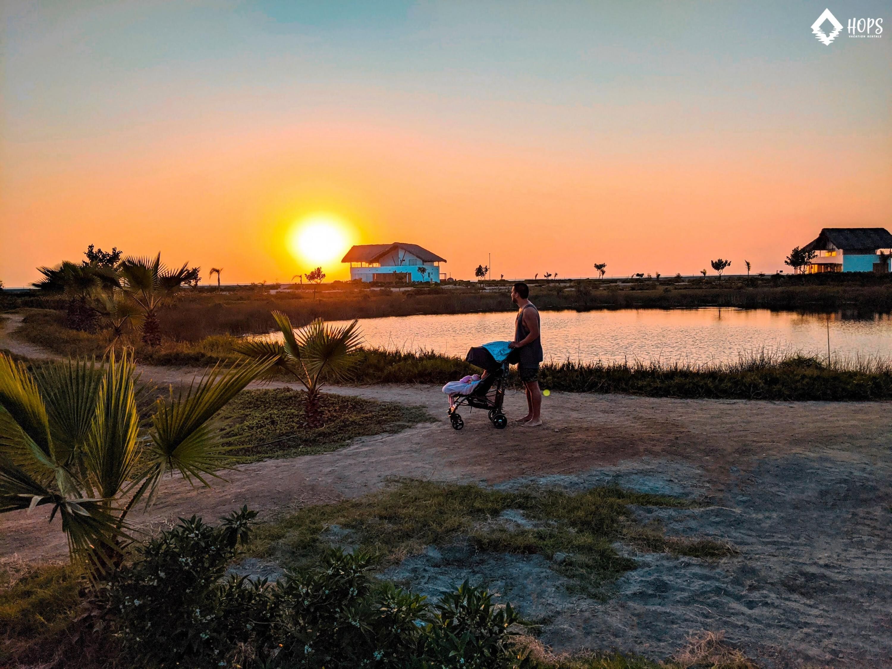 Atardecer sobre una masa de agua con casas al fondo.