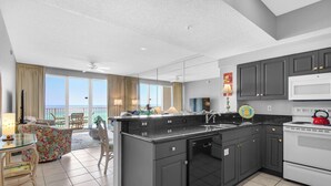 A modern kitchen with a central island, dark cabinetry, and a view to the outside.