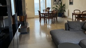 Un saló modern amb un sofà, taula de menjador, cadires i una cuina amb armaris i un frigorífic.