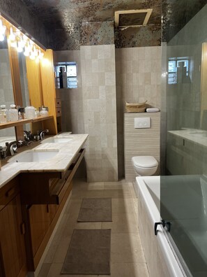 A modern bathroom with a large vanity, a bathtub, and a shower area.