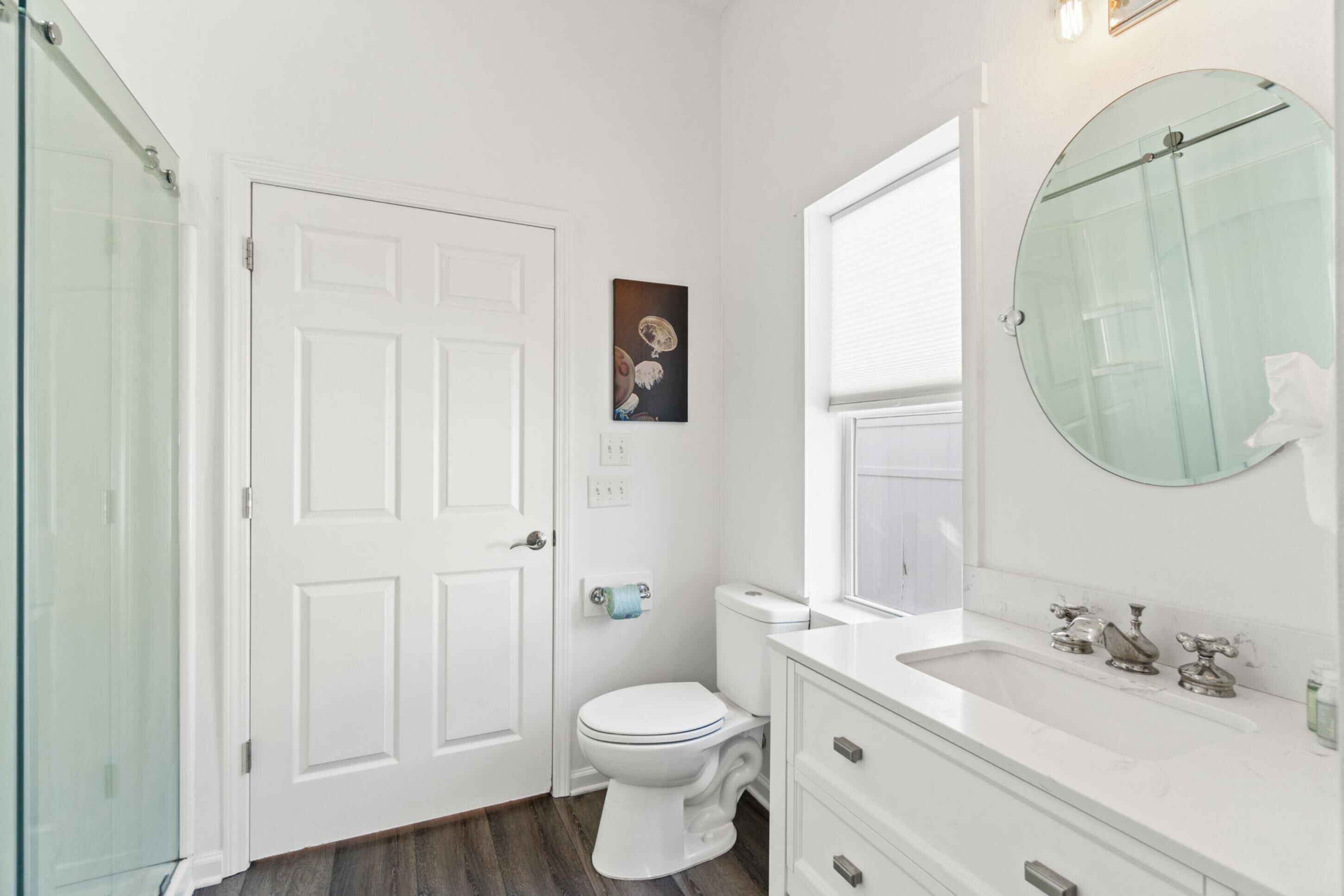 Un baño con inodoro y lavamanos blancos, y una cabina de ducha de vidrio.