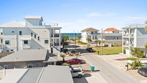 A coastal residential area with multi-story buildings, a clear sky, and a view of the ocean. - Beach House - The Sandcastle by PHG (Panama City Beach)