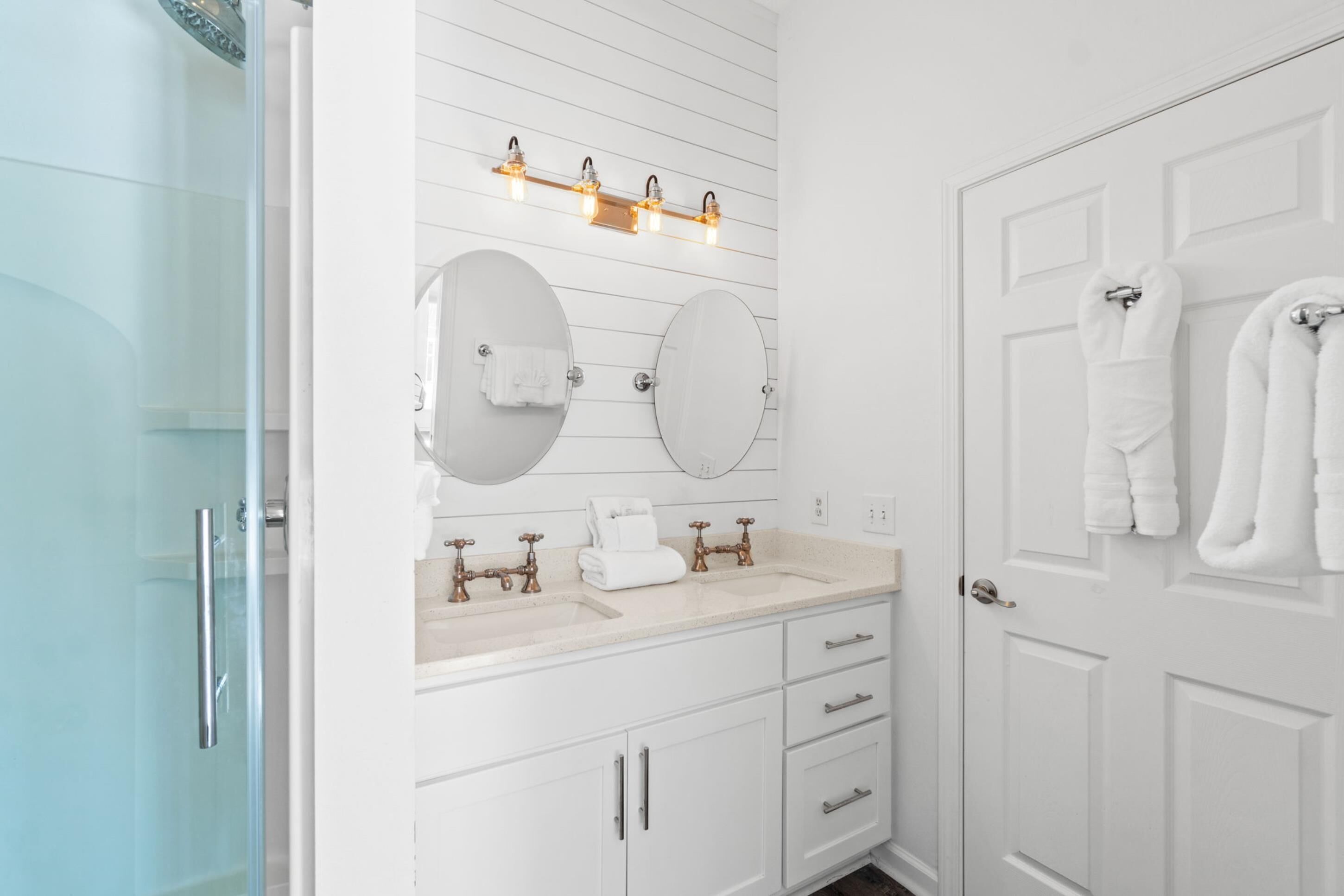 Une salle de bain avec deux lavabos, un miroir et un porte-serviettes.