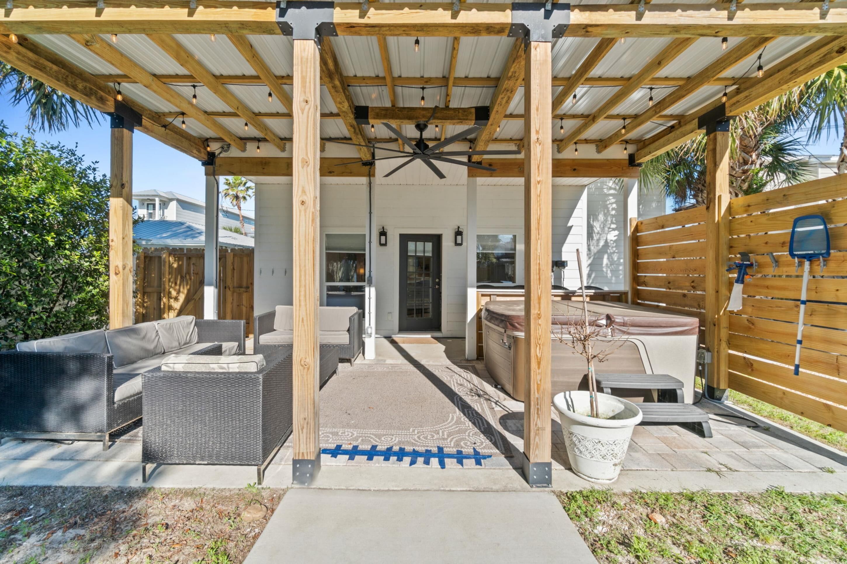 Ein Terrassenbereich im Freien mit Holz-Pergola, Sitzgelegenheiten und Deckenventilator.