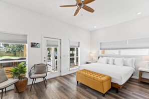 A modern bedroom with a large bed, a ceiling fan, and a view of the outdoors. - Beach House - The Sandcastle by PHG (Panama City Beach)