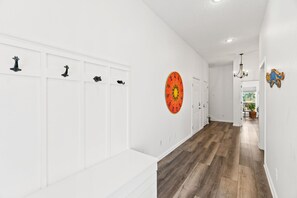 A hallway with white walls, a wooden floor, and a door at the end. - Beach House - The Sandcastle by PHG (Panama City Beach)