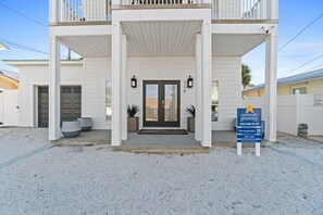 A two-story building with a covered entrance, a garage, and a sign indicating it is a vacation rental. - Beach House - The Sandcastle by PHG (Panama City Beach)