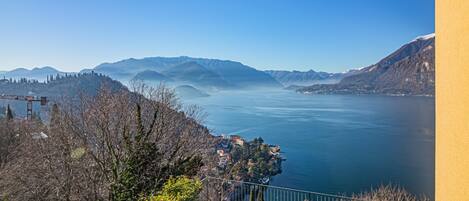 A panoramic view of a lake with mountains in the background and a small settlement on the shore.