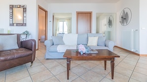 A living room with a brown leather sofa, a grey sofa with white cushions, and a wooden coffee table with a floral arrangement. - Sunny Varenna Apartment (Perledo)