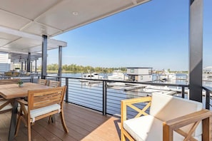 Um terraço com área de estar ao ar livre, vista para a marina e um edifício ao fundo.
