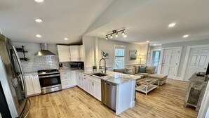 Une cuisine moderne avec des armoires blanches, des appareils en acier inoxydable et un plancher en bois.