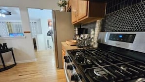 Een keuken met een roestvrijstalen fornuis, houten kasten en een uitzicht op de aangrenzende eetruimte.