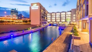 A modern hotel with a pool, a bridge, and a cityscape in the background. - Contemporary Cape Town Gem- No Loadshedding (Cape Town)