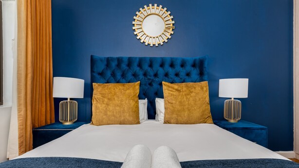 A bed with a tufted headboard, two bedside lamps, and two pillows. - Chic Beachfront Oasis - Balcony - Netflix (Cape Town)