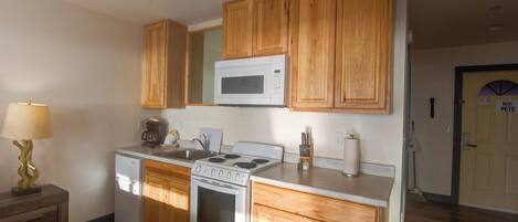 A compact kitchen with wooden cabinets, a microwave, stove, and refrigerator.