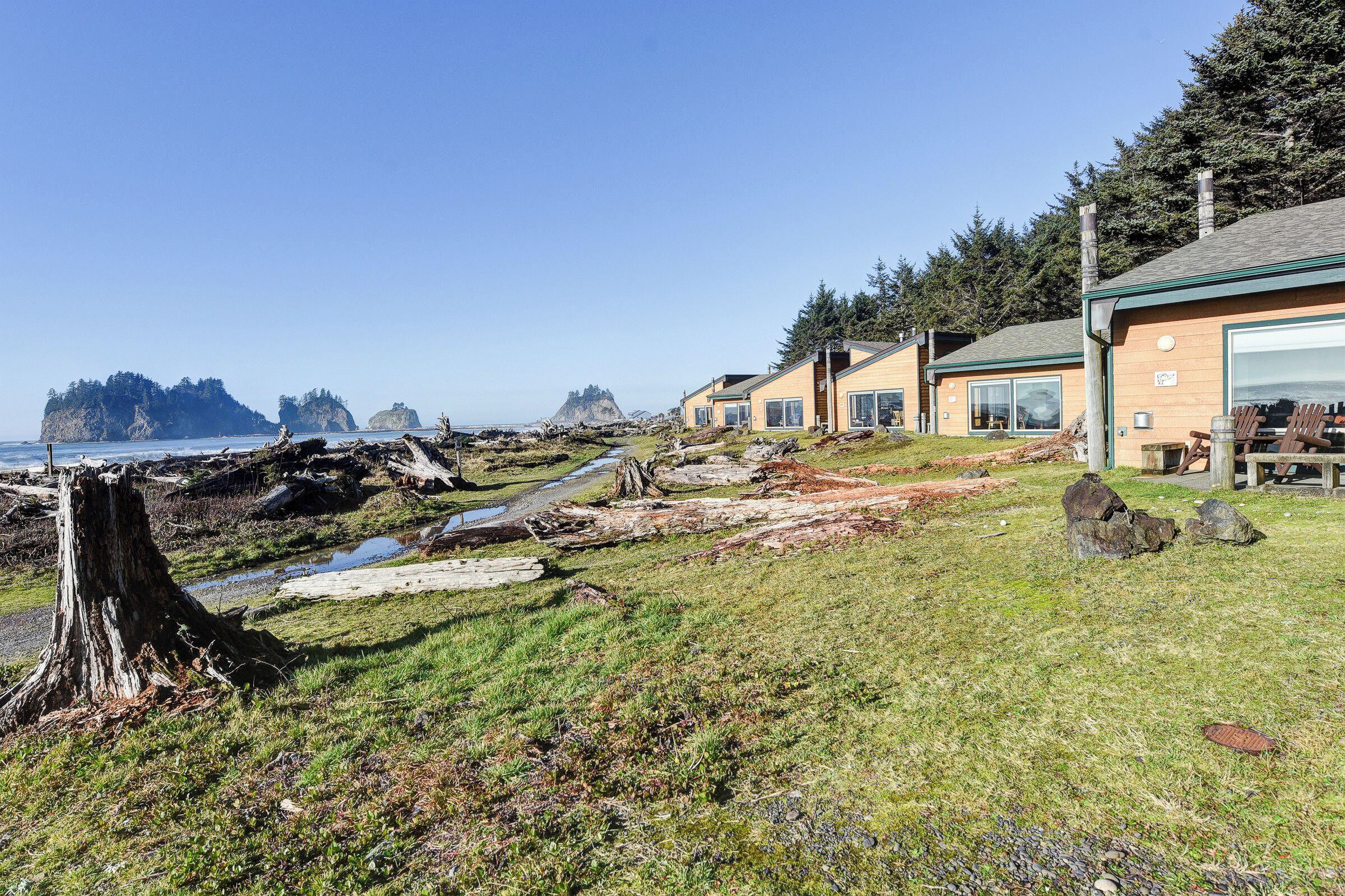A coastal property with a grassy area, wooden structures, and a view of the ocean and distant islands.