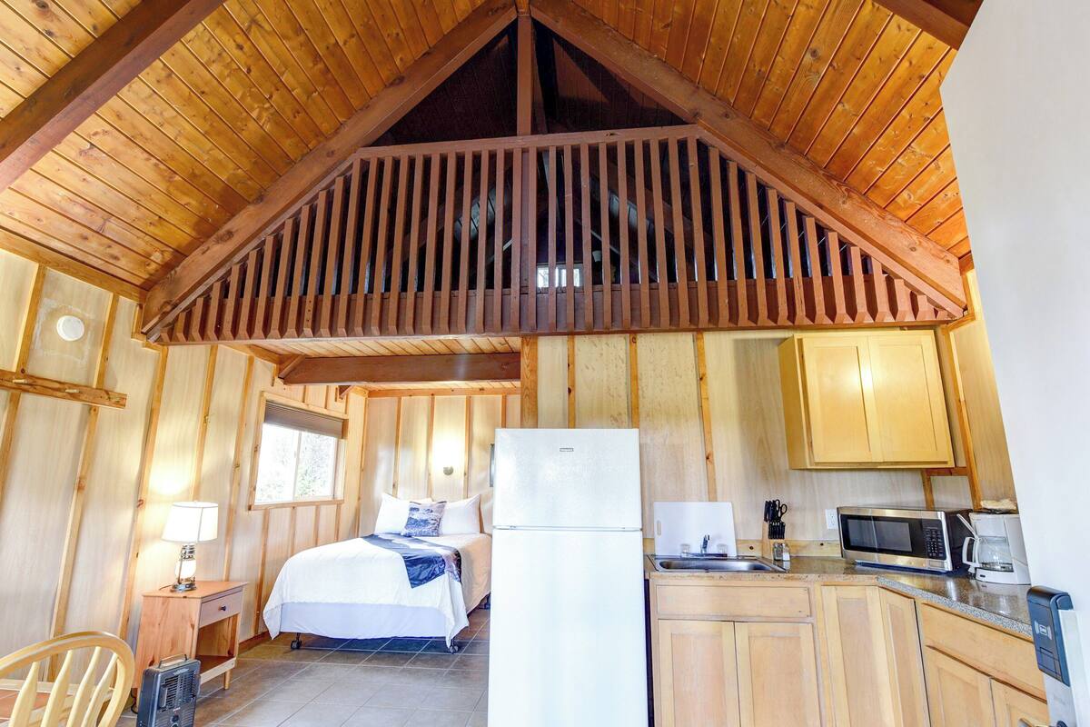 A wooden cabin with a kitchen, a bed, and a dining area.