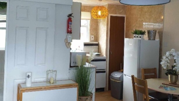 A compact kitchen with a refrigerator, stove, and a hanging light fixture. - 2 Bed Chalet Sleeps 5 - Pets, Parking, Near Beach (Great Yarmouth)