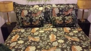 A bed with a floral and animal print bedspread, flanked by two nightstands with lamps. - 2 Bed Chalet Sleeps 5 - Pets, Parking, Near Beach (Great Yarmouth)