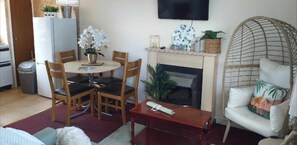 A living room with a round wooden table, four chairs, a sofa, a TV mounted on the wall, and a fireplace. - 2 Bed Chalet Sleeps 5 - Pets, Parking, Near Beach (Great Yarmouth)