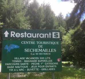 A sign for a restaurant and tourist center in Sechemailles, including amenities like tennis, a nursery, and a first-category beach.