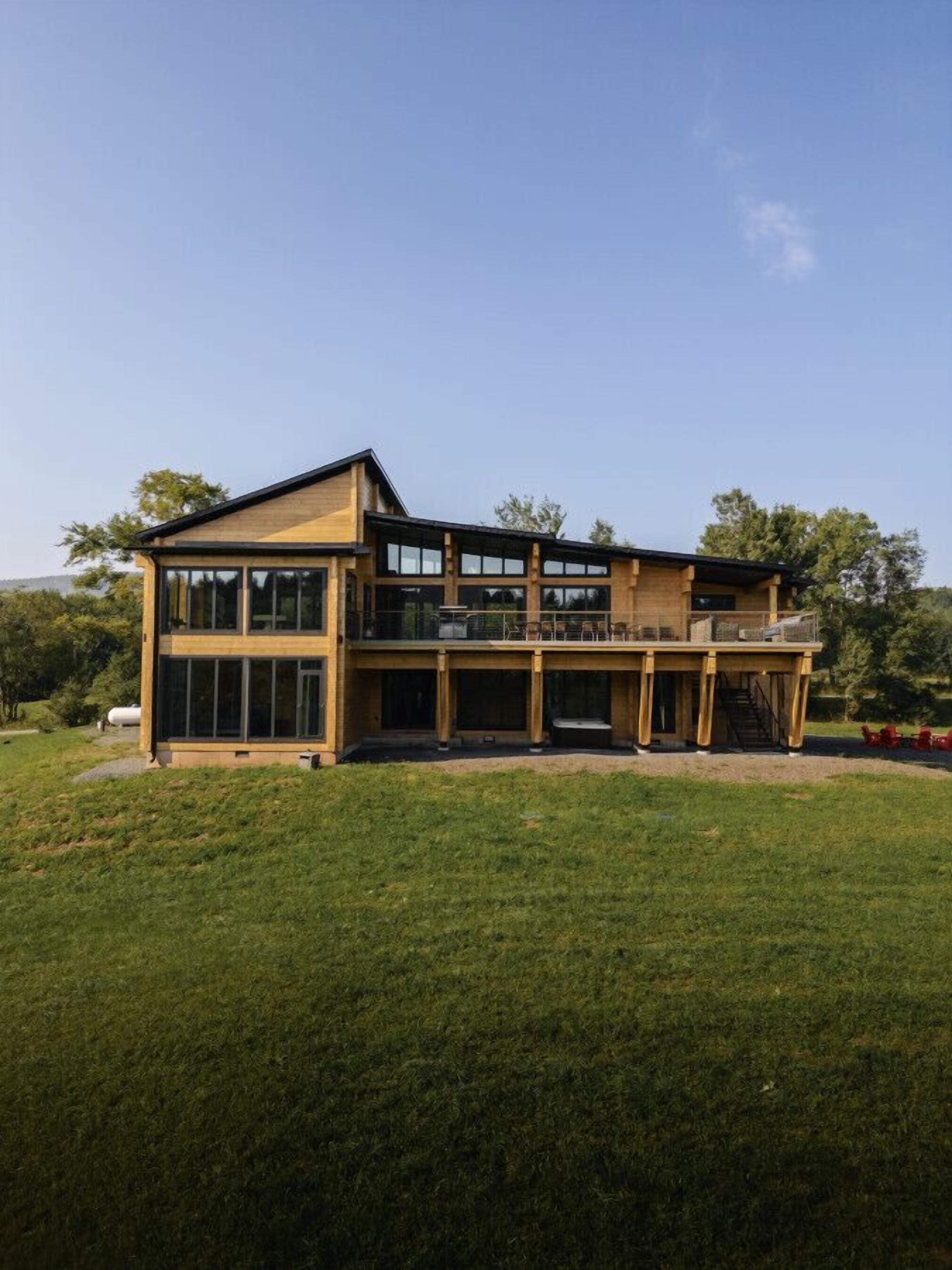 A modern two-story house with large windows and a covered patio area.
