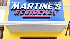 Un edificio con un cartel de Martine's Residency, un oasis de confort y lujo, ubicado en la calle Muthumariamman Koil, número 87, Puducherry - 01.