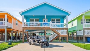 A beachfront property with a two-story house, a covered parking area, and a sign indicating 'Wait 'n Sea'. - `Enjoy the Sun in Your Private Pool, Charcoal Grill & Fire Pit for Cozy Evenings – Free Golf Cart, Private Pool, Just Steps from the Beach!` (Port Aransas)