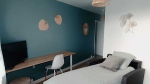 Ein modernes Schlafzimmer mit Bett, Schreibtisch und Fernseher.