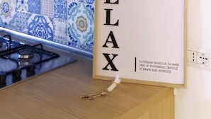 A kitchen with a decorative backsplash, a white cabinet, and a framed word 'RELAX' with its definition. - B&B Angelica - Apartment (Bacoli)