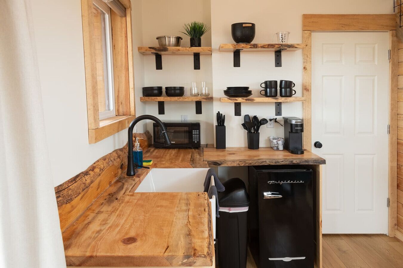 A compact kitchen with wooden countertops, a sink, a microwave, and a coffee maker.