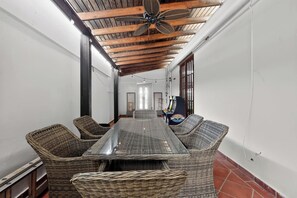 A long dining table with wicker chairs, a ceiling fan, and a view of a corridor. - Massive 3 bedroom with Pool (Palmas del Mar)