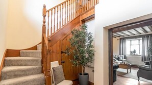 Un escalier avec des rampes en bois, une plante en pot, une chaise et une vue sur un salon avec un canapé et une table basse.