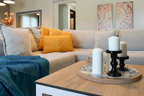 Un salon avec un canapé, des coussins, une table basse et un porte-bougie.