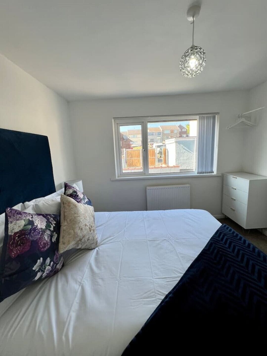 Ein Schlafzimmer mit Bett, Fenster, Heizkörper und Schminktisch.