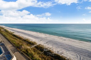 Een strand met een houten promenade, een zwembad en een helder uitzicht op de oceaan.