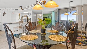Un espace repas avec une table en verre entourée de chaises, une plante en pot et des luminaires suspendus.