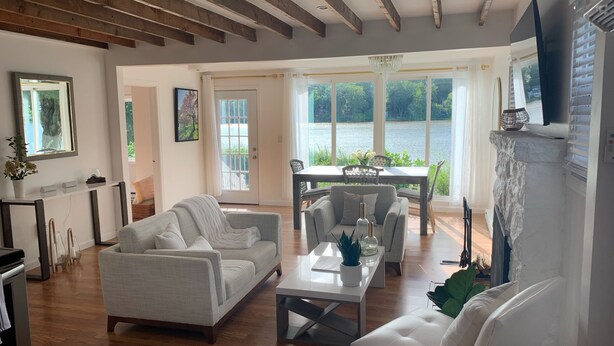 Una sala de estar amplia con chimenea, un comedor con vistas a un lago y una zona de estar acogedora.