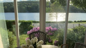 Una mesa con un jarrón de flores y vistas a un lago a través de amplias ventanas.
