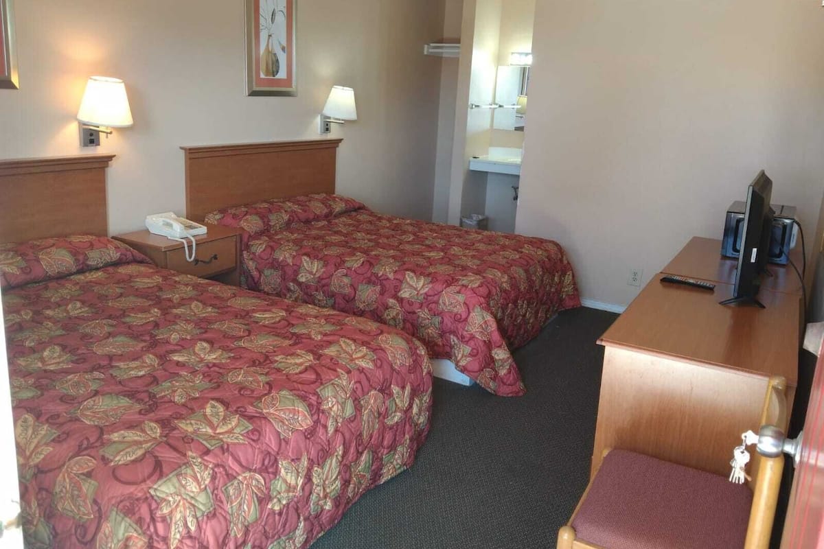 Ein Hotelzimmer mit zwei Betten, einem Schreibtisch, einem Fernseher und einem Telefon.